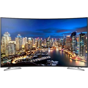 Samsung 55HU7100 Ultra HD 4K LED televizyon, şehir manzarası ekranında; siyah renkli TV standı ile vitrin görünüyor
