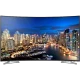 Samsung 55HU7100 Ultra HD 4K LED televizyon, şehir manzarası ekranında; siyah renkli TV standı ile vitrin görünüyor
